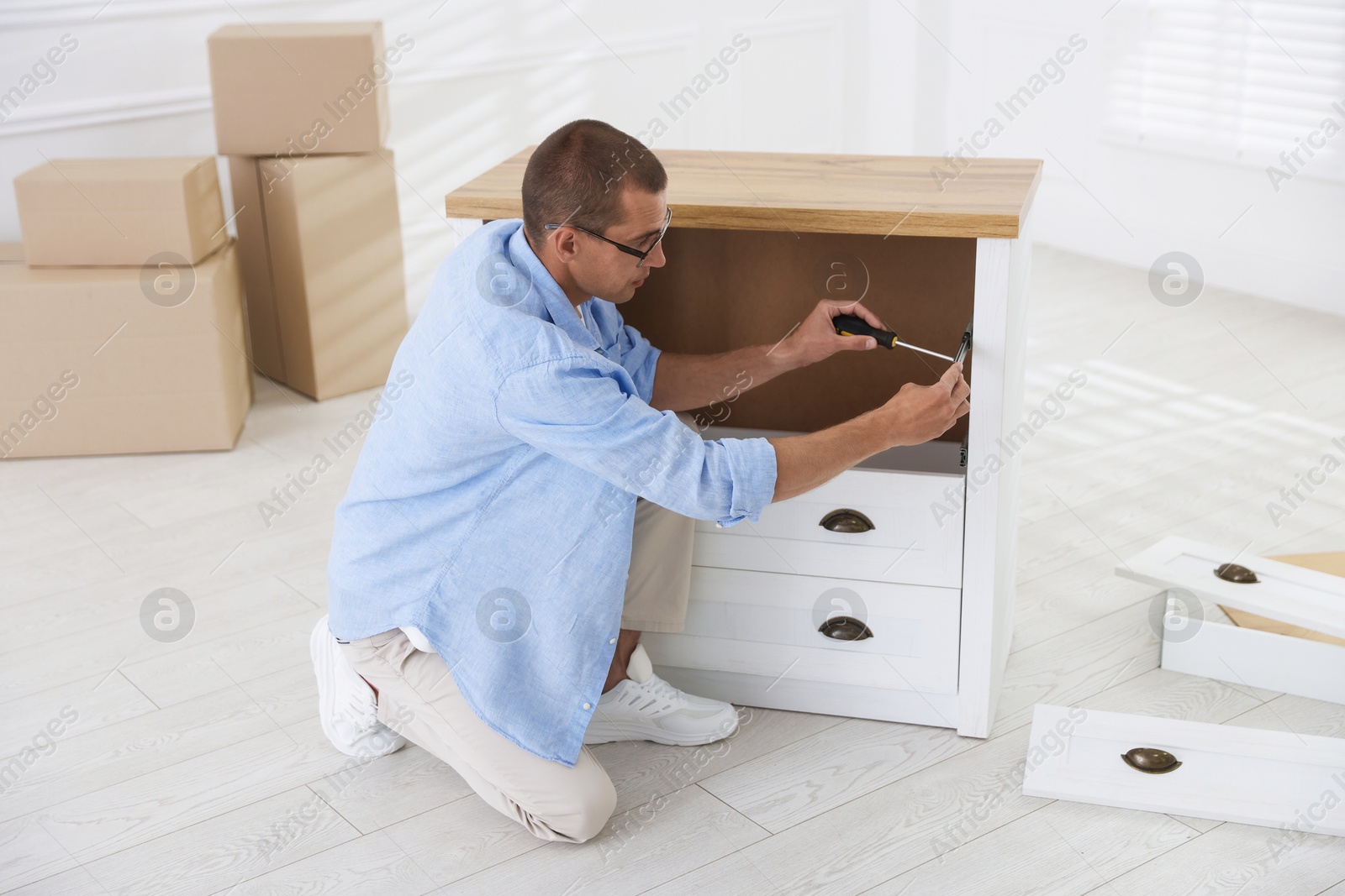 Man assembling furniture with screwdriver on floor at home Photo of Man assembling furniture with screwdriver on floor at home