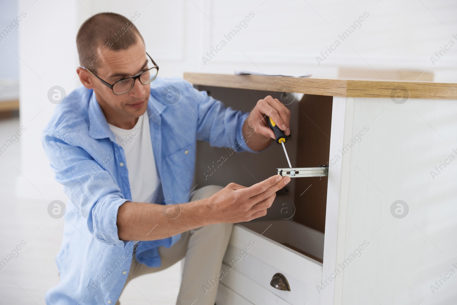 Man assembling furniture with screwdriver at home Photo of Man assembling furniture with screwdriver at home