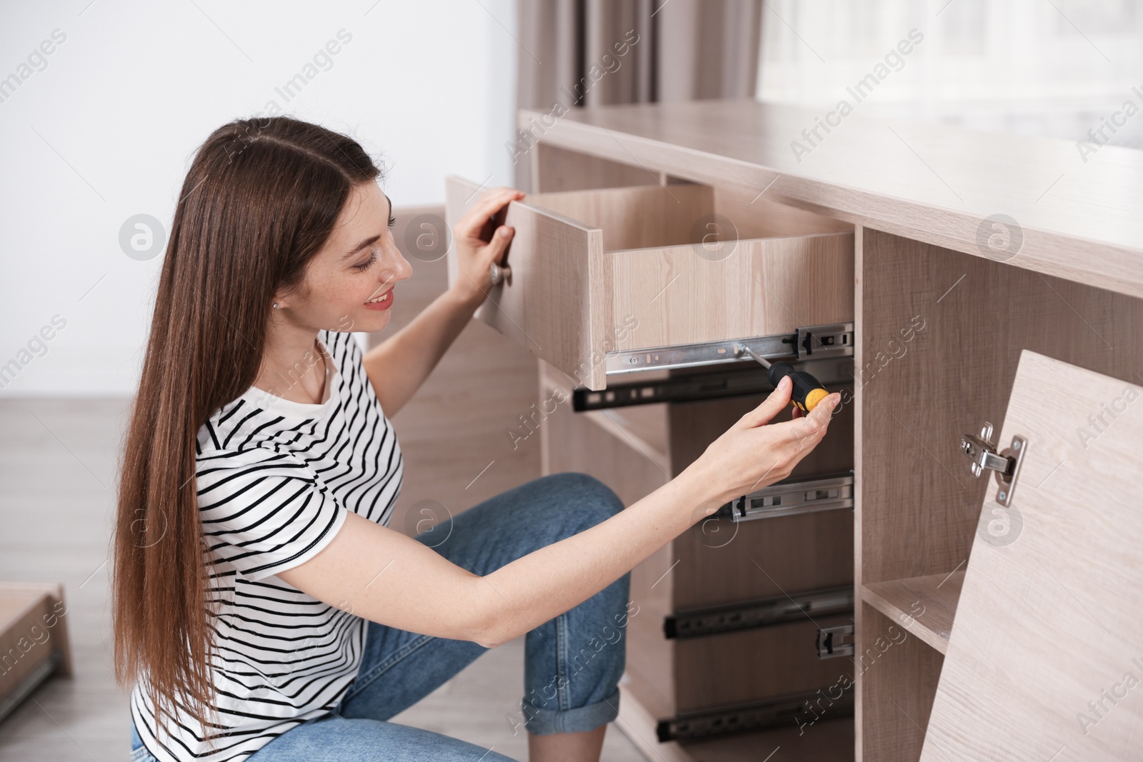 Smiling woman assembling furniture with screwdriver at home Photo of Smiling woman assembling furniture with screwdriver at home