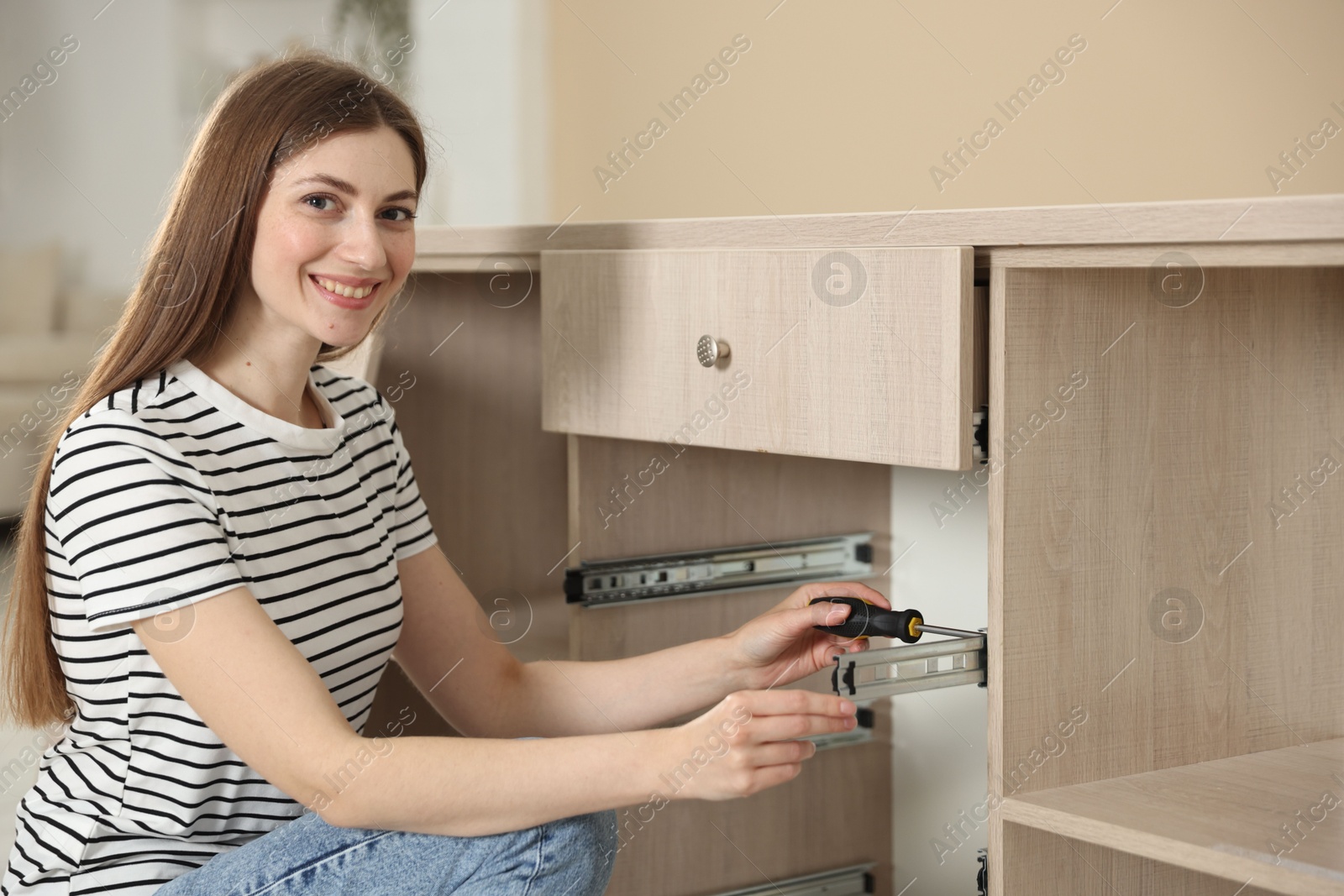 Smiling woman assembling furniture with screwdriver at home Photo of Smiling woman assembling furniture with screwdriver at home