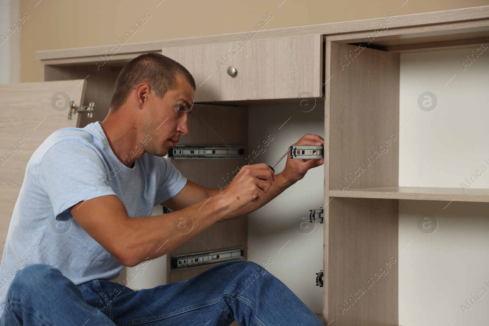 Man assembling furniture with screwdriver at home Photo of Man assembling furniture with screwdriver at home