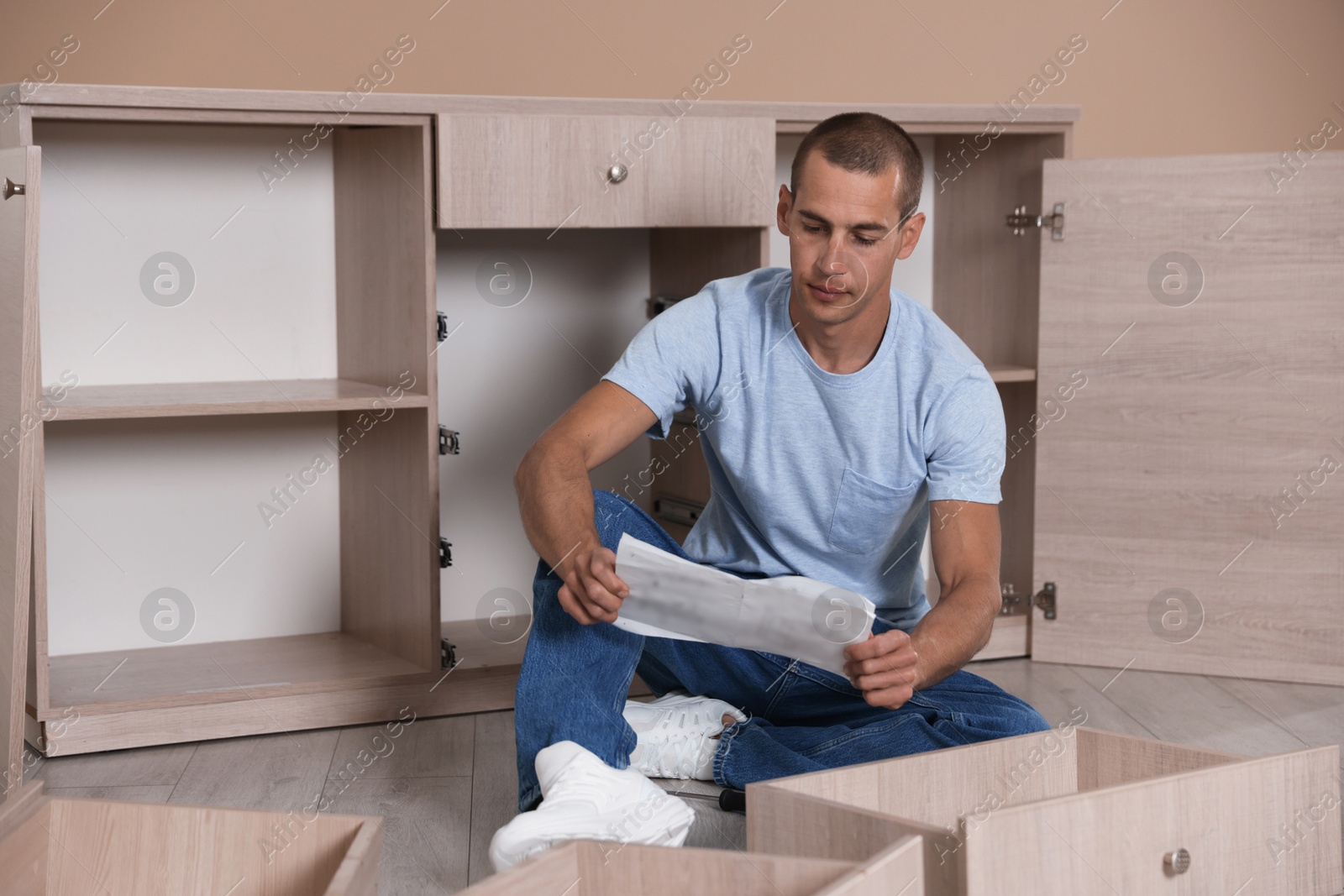 Man with manual assembling furniture on floor at home Photo of Man with manual assembling furniture on floor at home