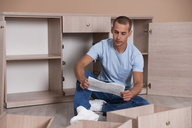 Photo of Man with manual assembling furniture on floor at home