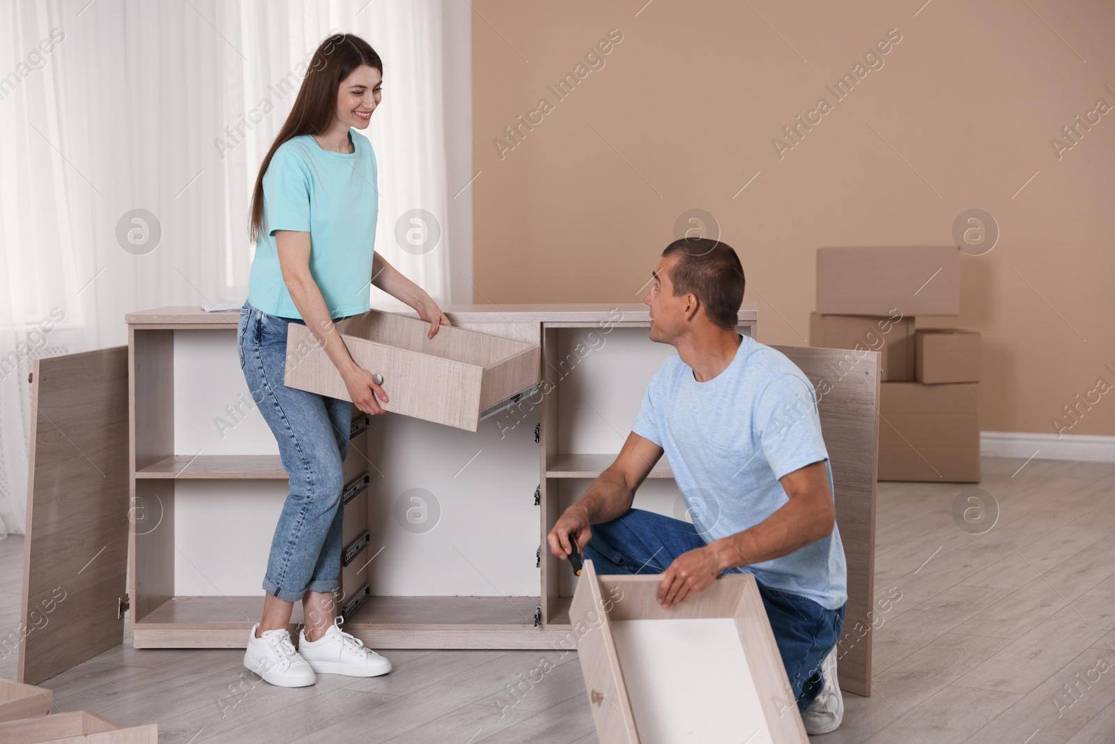 Happy couple assembling furniture on floor at home Photo of Happy couple assembling furniture on floor at home