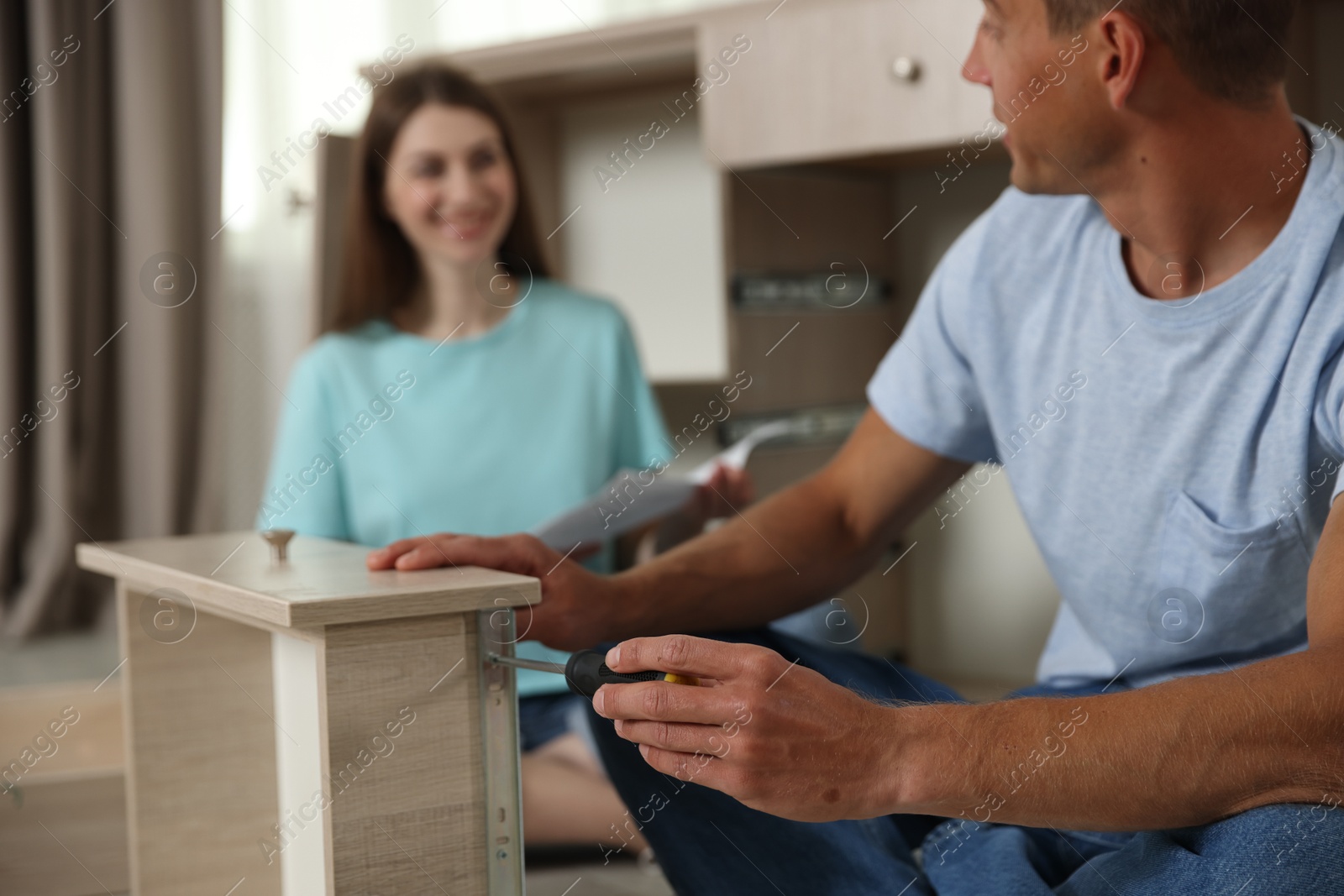 Couple assembling furniture with screwdriver on floor at home, selective focus Photo of Couple assembling furniture with screwdriver on floor at home, selective focus