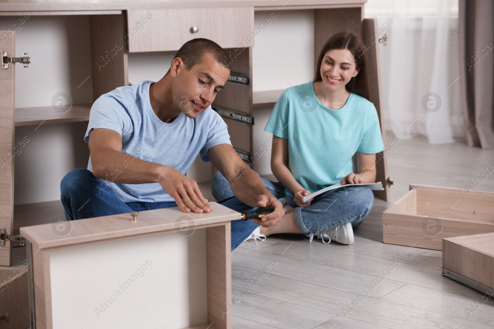 Happy couple assembling furniture on floor at home Photo of Happy couple assembling furniture on floor at home