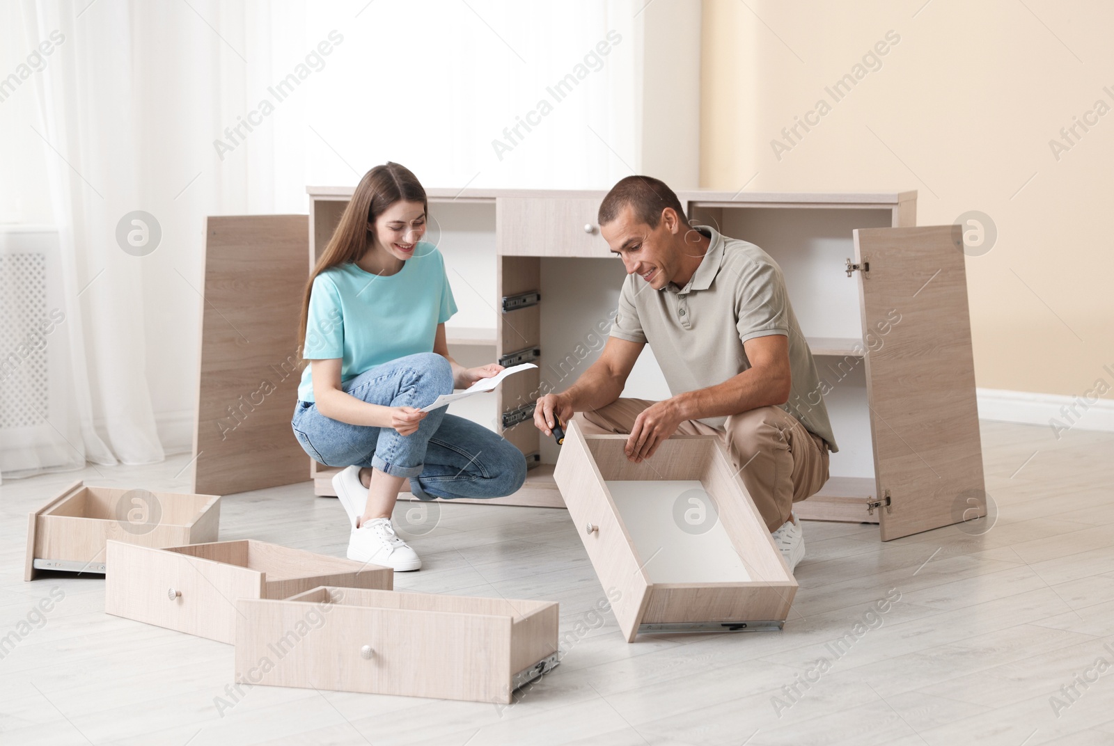 Happy couple with manual assembling furniture on floor at home Photo of Happy couple with manual assembling furniture on floor at home