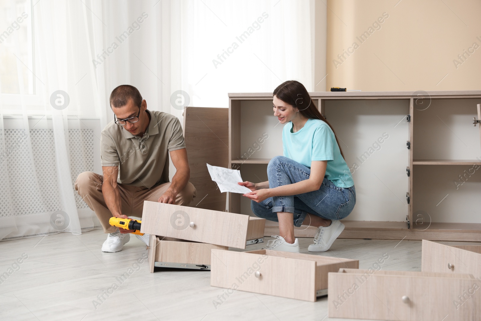 Happy couple with manual assembling furniture on floor at home Photo of Happy couple with manual assembling furniture on floor at home