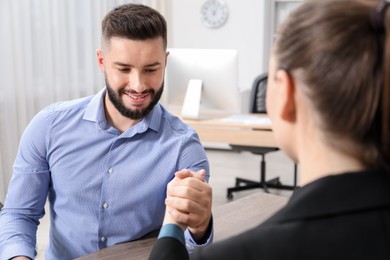 Photo of Businesspeople arm wrestling at wooden table in office
