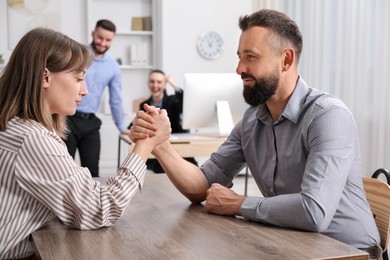 Photo of Businesspeople arm wrestling at wooden table in office, selective focus