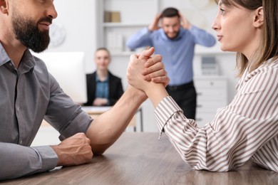 Photo of Businesspeople arm wrestling at wooden table in office, selective focus