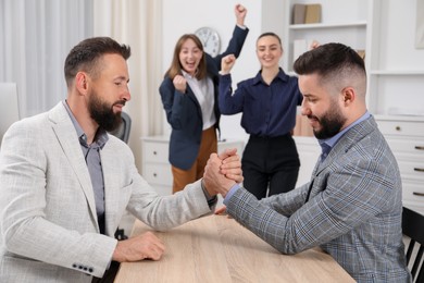 Photo of Businessmen arm wrestling at wooden table in office, selective focus