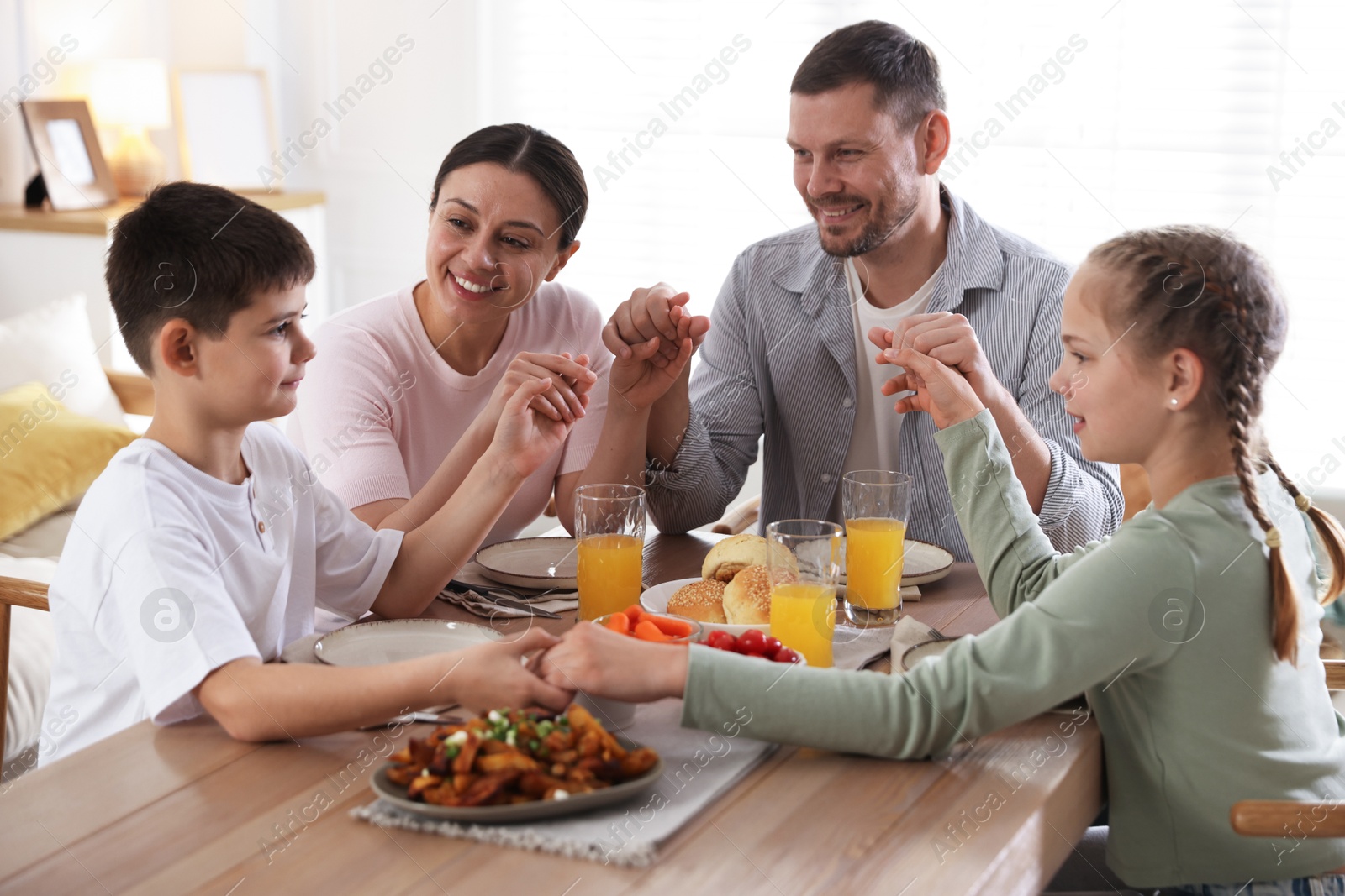 Photo of Family praying together before dinner at table indoors