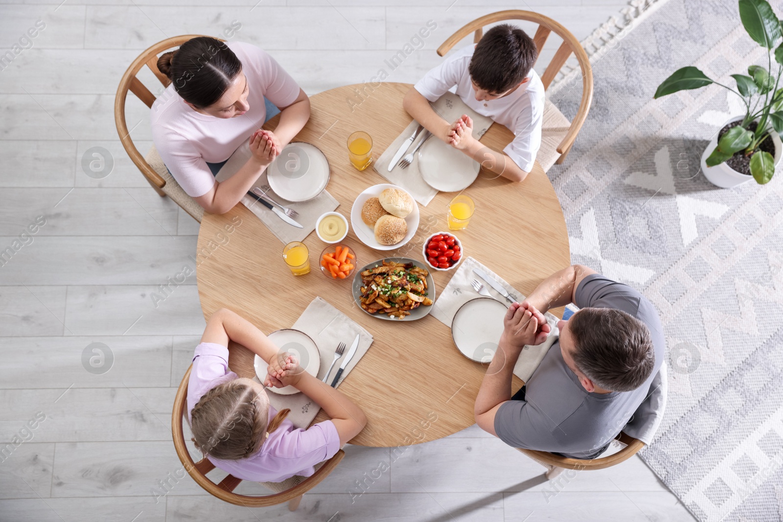 Family praying together before dinner at table indoors, above view Photo of Family praying together before dinner at table indoors, above view