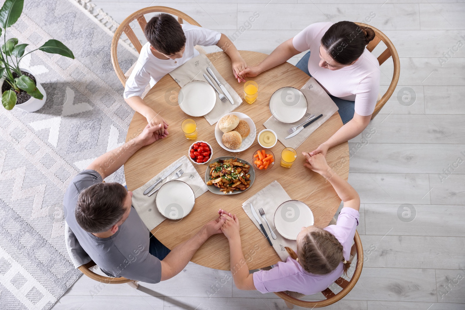 Family praying together before dinner at table indoors, above view Photo of Family praying together before dinner at table indoors, above view