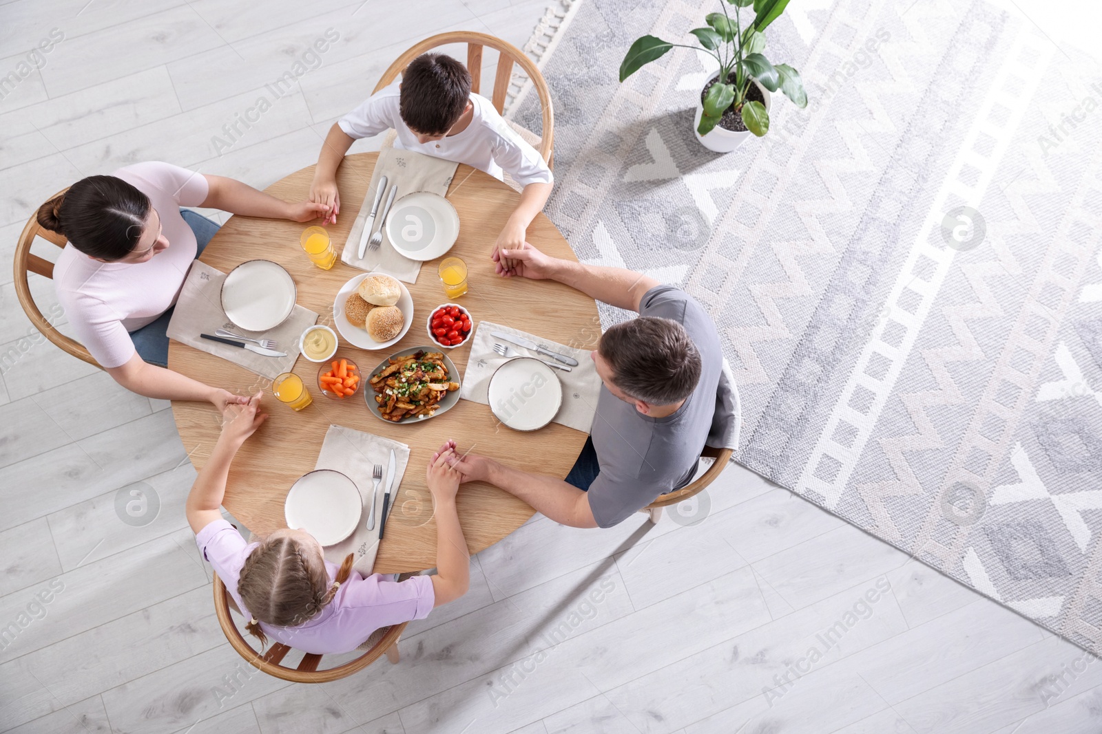 Family praying together before dinner at table indoors, above view Photo of Family praying together before dinner at table indoors, above view