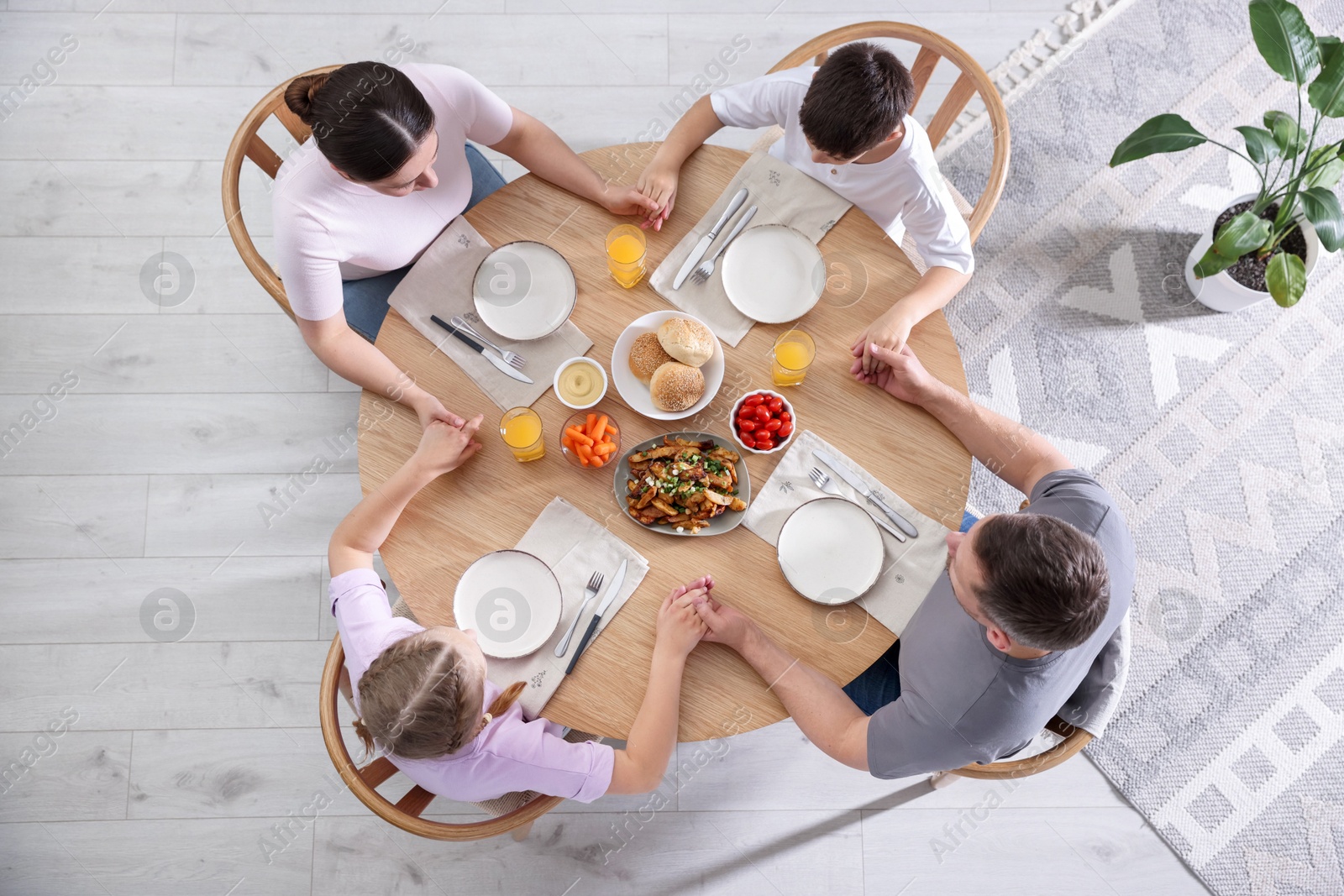 Family praying together before dinner at table indoors, above view Photo of Family praying together before dinner at table indoors, above view