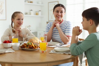 Photo of Family praying together before dinner at table indoors