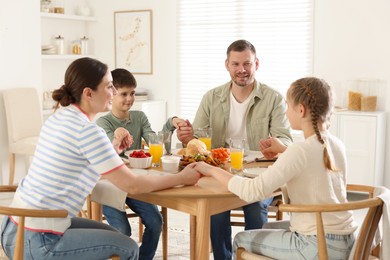 Photo of Family praying together before dinner at table indoors