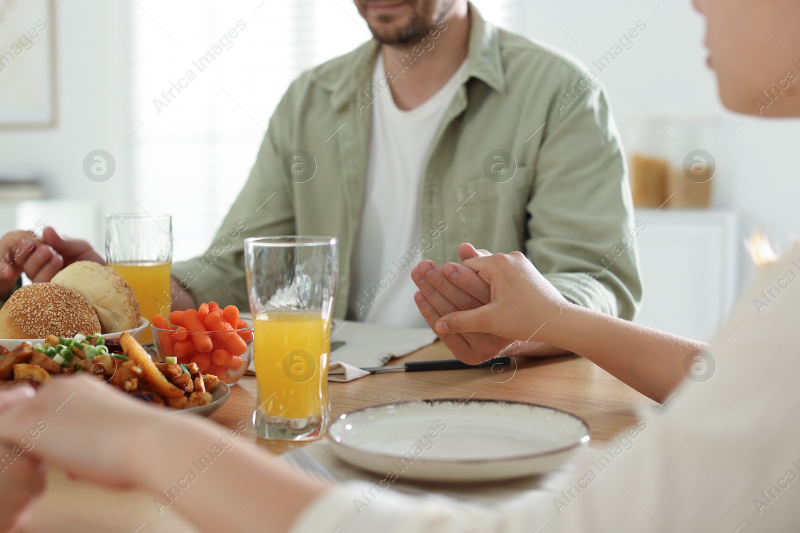 Family praying together before dinner at table indoors, closeup Photo of Family praying together before dinner at table indoors, closeup