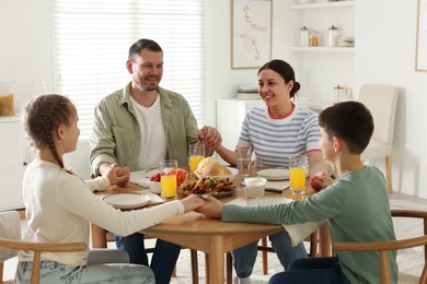Photo of Family praying together before dinner at table indoors