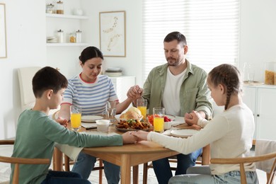 Photo of Family praying together before dinner at table indoors