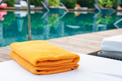 Photo of Beach towels on sun lounger near outdoor swimming pool, space for text. Luxury resort