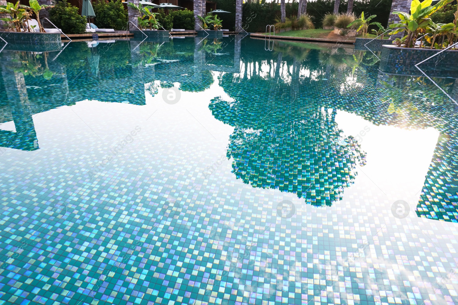 Outdoor swimming pool with umbrellas and sunbeds at resort Photo of Outdoor swimming pool with umbrellas and sunbeds at resort