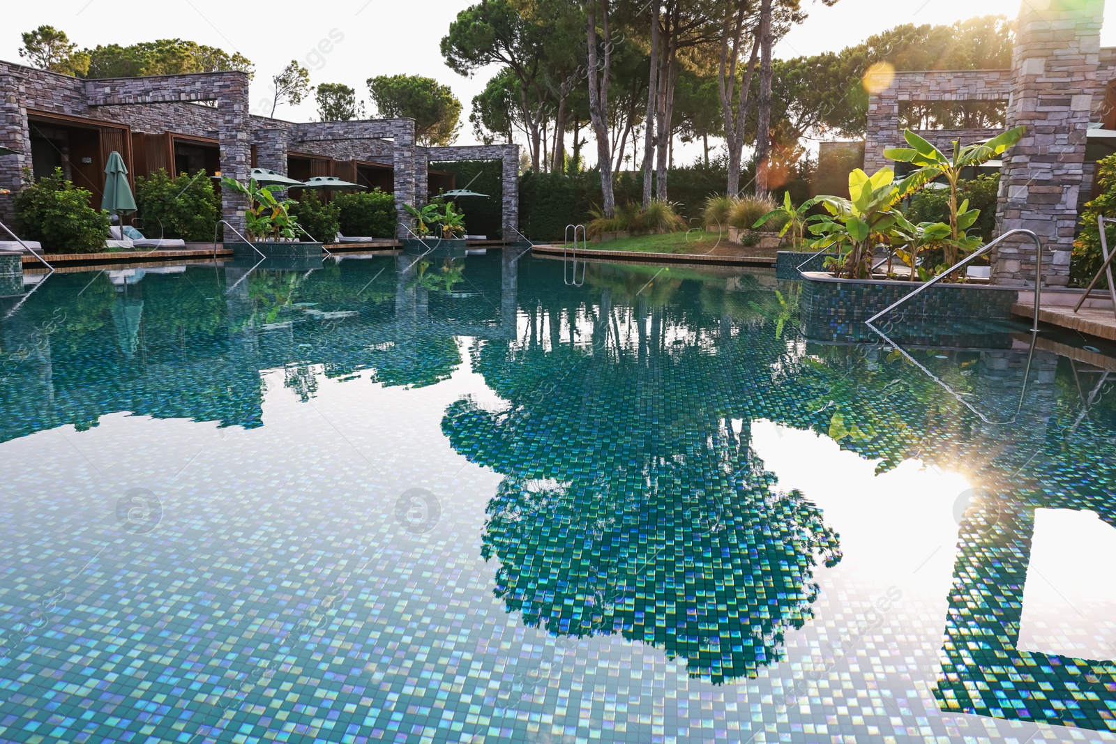 Outdoor swimming pool with umbrellas and sunbeds at resort Photo of Outdoor swimming pool with umbrellas and sunbeds at resort