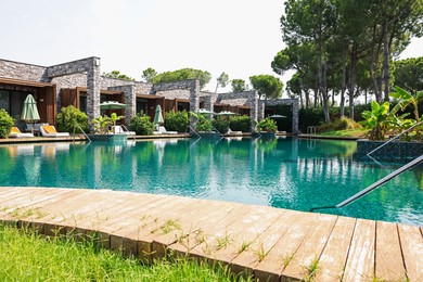Photo of Outdoor swimming pool with wooden deck, sunbeds and umbrellas at resort