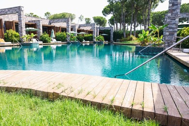 Photo of Outdoor swimming pool with wooden deck, sunbeds and umbrellas at resort