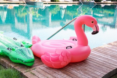 Photo of Floats in shape of crocodile and flamingo on wooden deck near swimming pool at luxury resort