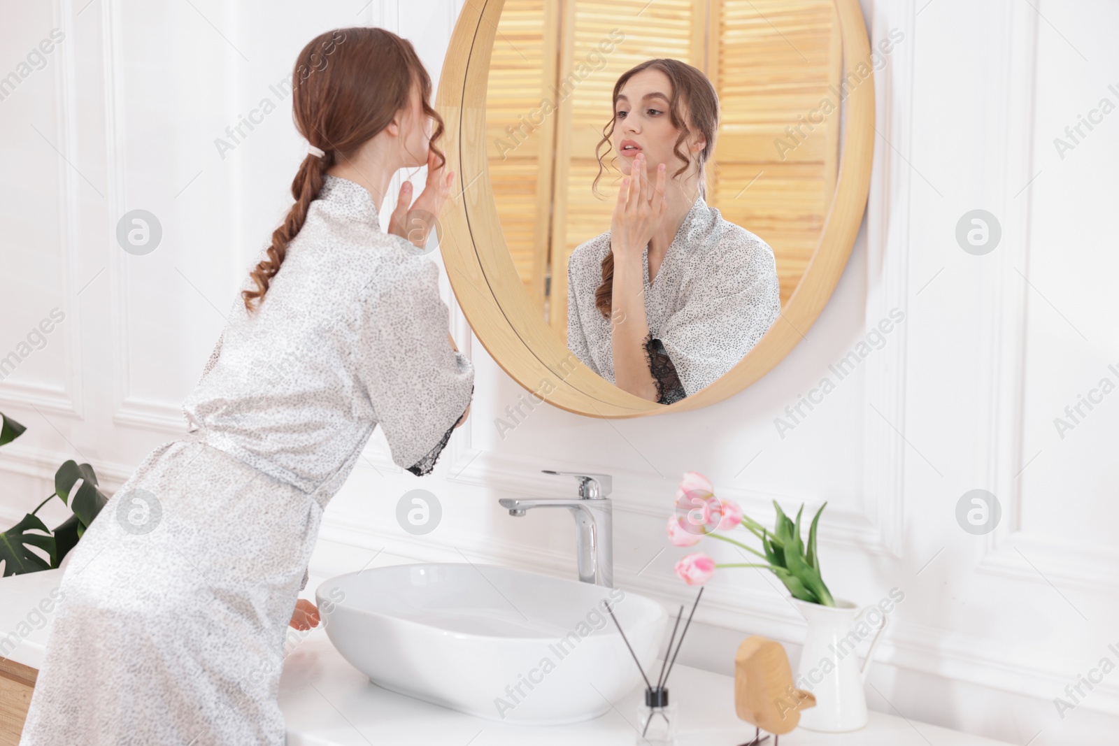 Photo of Beautiful woman looking at herself in mirror indoors