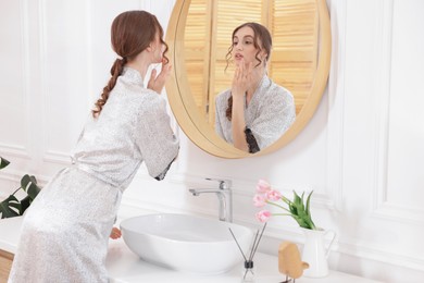 Photo of Beautiful woman looking at herself in mirror indoors