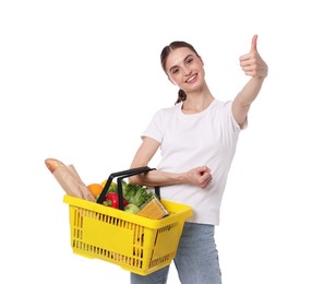 Photo of Woman with shopping basket full of products showing thumbs up on white background