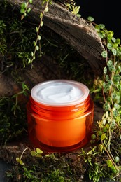Photo of Jar of moisturizing body cream on tree bark with plants, closeup
