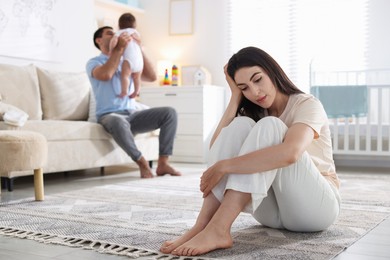 Photo of Woman suffering from postpartum depression and her husband with baby at home, selective focus