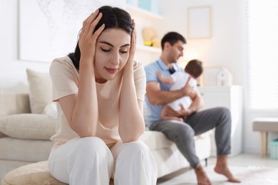 Photo of Woman suffering from postpartum depression and her husband with baby at home, selective focus