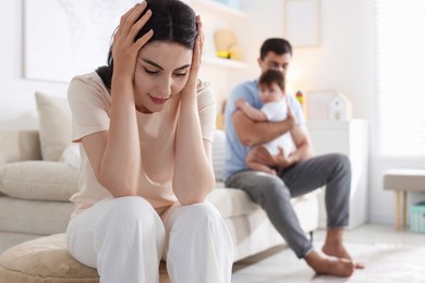 Photo of Woman suffering from postpartum depression and her husband with baby at home, selective focus