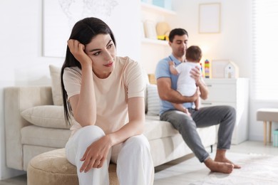 Photo of Woman suffering from postpartum depression and her husband with baby at home, selective focus