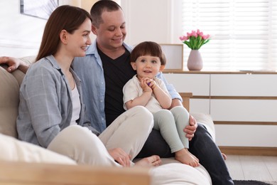 Photo of Cute little boy and his parents on sofa at home. Lovely family