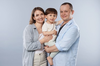 Photo of Happy parents and their baby boy on light grey background. Lovely family
