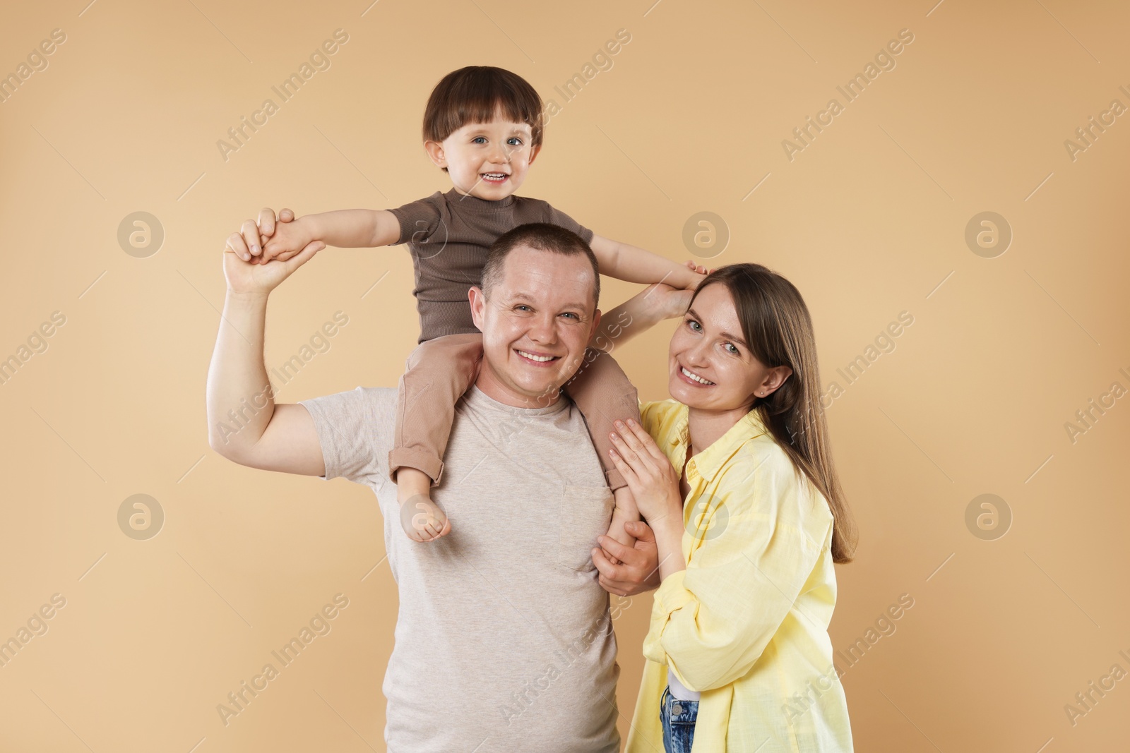 Happy parents and their baby boy on beige background. Lovely family Photo of Happy parents and their baby boy on beige background. Lovely family