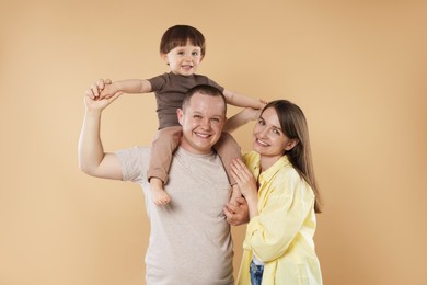 Photo of Happy parents and their baby boy on beige background. Lovely family