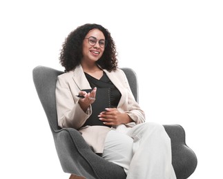 Photo of Professional psychologist with notebook and pen in armchair on white background