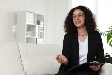 Photo of Professional psychologist with clipboard and pen in office, space for text