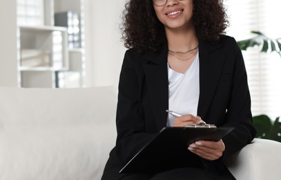 Photo of Professional psychologist with clipboard and pen in office, closeup. Space for text