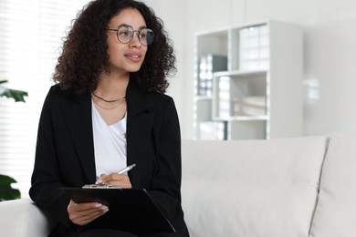 Photo of Professional psychologist with clipboard and pen in office, space for text