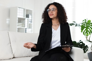 Photo of Professional psychologist with clipboard working in office