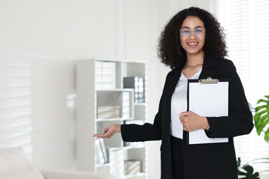 Photo of Professional psychologist with clipboard and pen in office, space for text